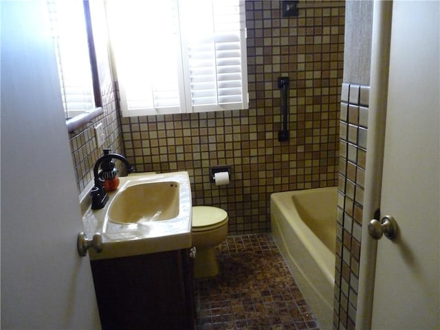 bathroom featuring vanity, toilet, a bath, and tile walls