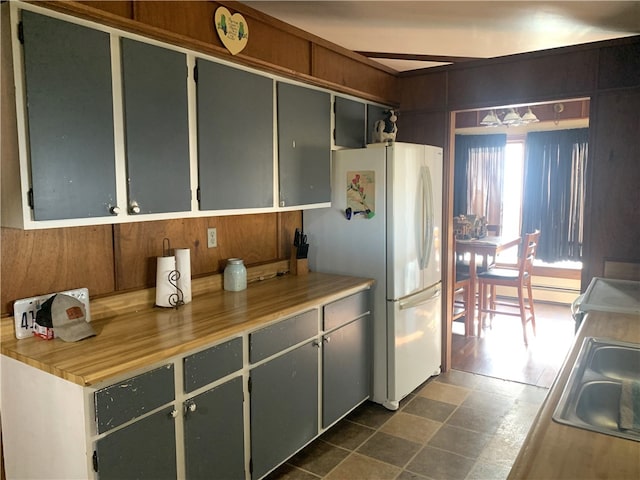 kitchen with gray cabinets, light countertops, stove, freestanding refrigerator, and a sink