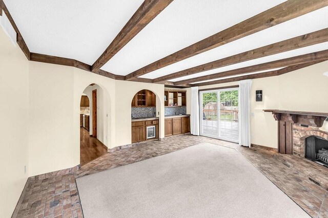4554 Nicklaus Ct, Decatur, IL 62526 - unfurnished living room with a stone fireplace, bar, baseboards, beam ceiling, and arched walkways