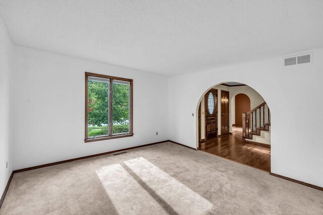 4554 Nicklaus Ct, Decatur, IL 62526 - spare room featuring carpet flooring, arched walkways, baseboards, and stairs