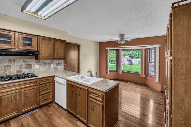 4554 Nicklaus Ct, Decatur, IL 62526 - kitchen with a sink, a peninsula, white dishwasher, brown cabinets, and ceiling fan