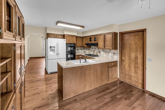 4554 Nicklaus Ct, Decatur, IL 62526 - kitchen with black appliances, a sink, a peninsula, brown cabinetry, and dark wood-style floors