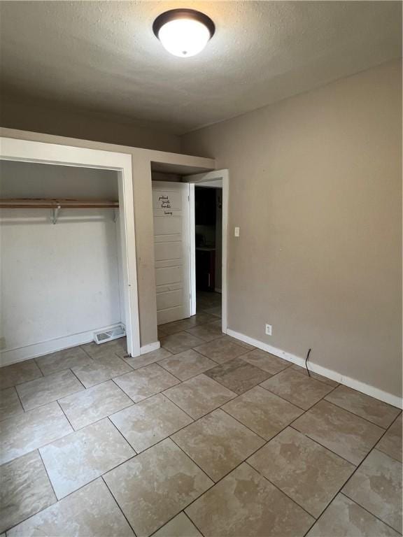 249 N 17th St, Decatur, IL 62521 - unfurnished bedroom with a textured ceiling, a closet, light tile patterned floors, and baseboards