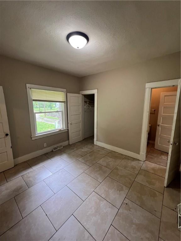 249 N 17th St, Decatur, IL 62521 - unfurnished bedroom featuring baseboards, a closet, a textured ceiling, and light tile patterned floors