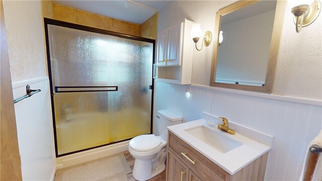 bathroom featuring vanity, an enclosed shower, and toilet