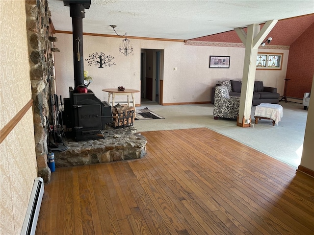 living room with hardwood / wood-style floors, lofted ceiling, a wood stove, and a baseboard radiator