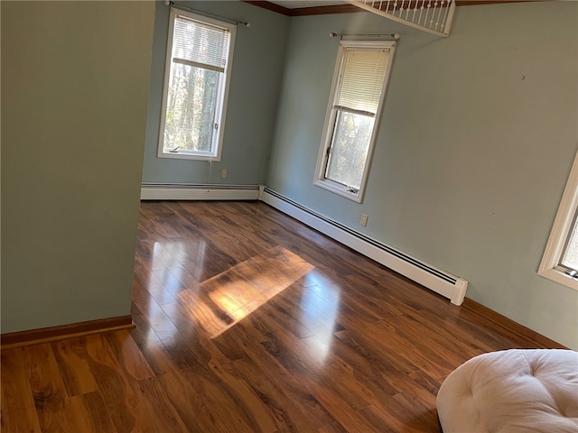 unfurnished room featuring crown molding, dark hardwood / wood-style flooring, and a baseboard heating unit