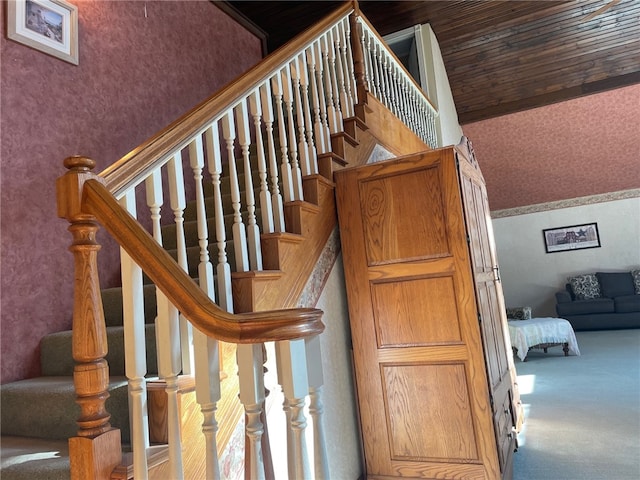 staircase featuring carpet, vaulted ceiling, and wood ceiling