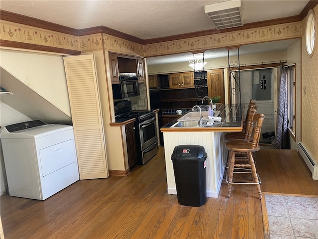 kitchen featuring dark hardwood / wood-style floors, washer / dryer, stainless steel range, and a baseboard radiator