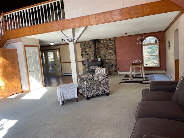 carpeted living room featuring a chandelier, a baseboard heating unit, a wood stove, and crown molding