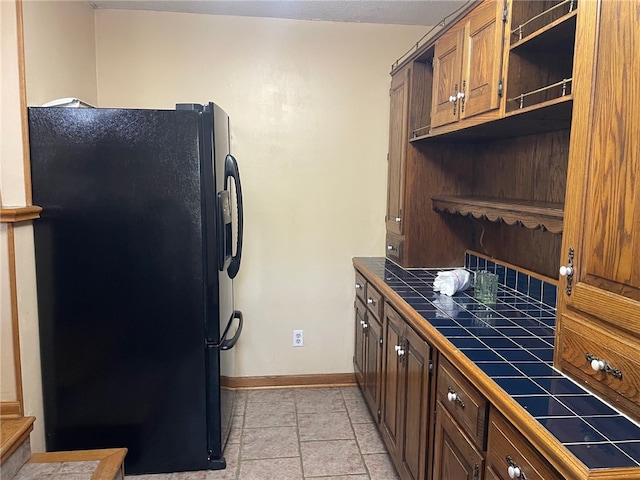 kitchen with black refrigerator and tile counters