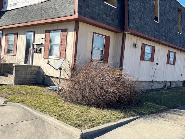 view of side of property with mansard roof and roof with shingles