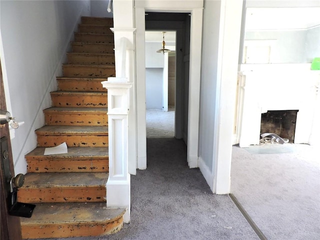 stairway featuring carpet and a fireplace