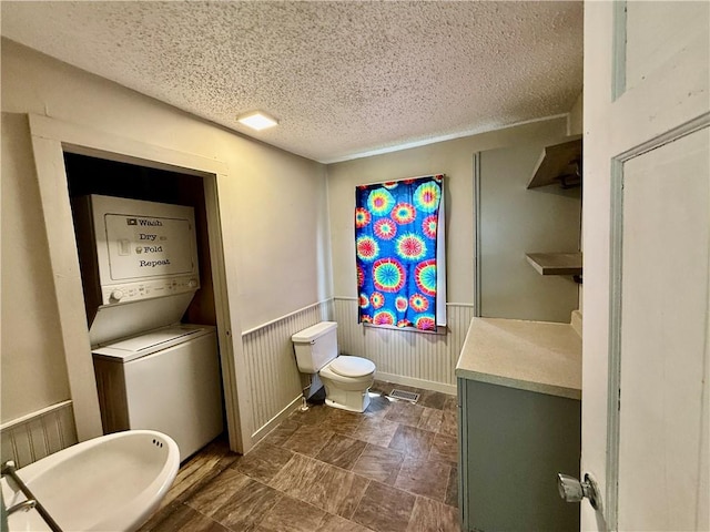 1250 S Lake Ridge Ave, Decatur, IL 62521 - bathroom featuring a textured ceiling, stacked washing machine and dryer, and wainscoting