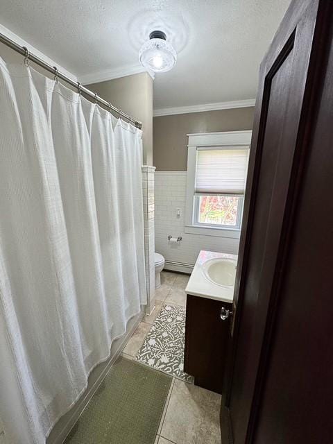 bathroom with tile patterned flooring, ornamental molding, toilet, tile walls, and baseboard heating