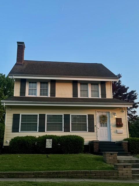 view of front of house with a chimney and a front lawn