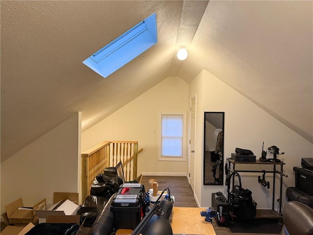 additional living space featuring vaulted ceiling with skylight, a textured ceiling, and wood finished floors