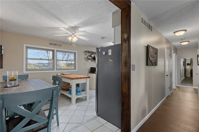 kitchen featuring a textured ceiling, light hardwood / wood-style flooring, ceiling fan, and stainless steel refrigerator