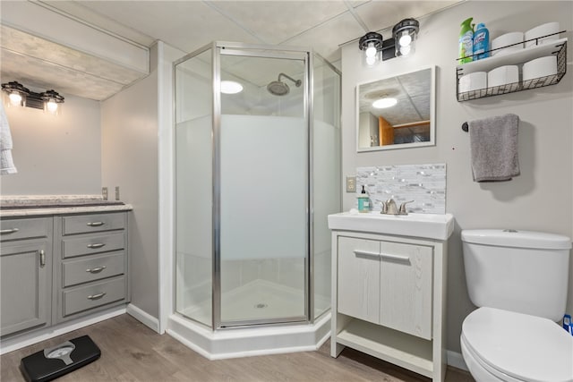 bathroom with hardwood / wood-style floors, vanity, toilet, and a shower with shower door