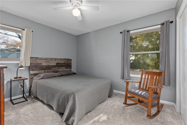 bedroom featuring light carpet, a textured ceiling, and ceiling fan