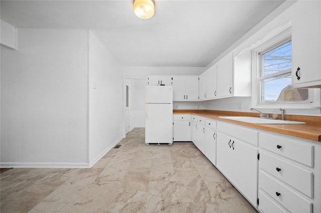 710 E Blackburn St, Paris, IL 61944 - kitchen featuring freestanding refrigerator, a sink, white cabinetry, and baseboards