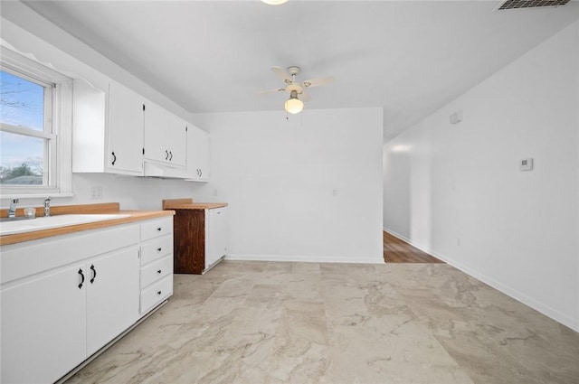 710 E Blackburn St, Paris, IL 61944 - kitchen with a sink, white cabinetry, light countertops, ceiling fan, and baseboards