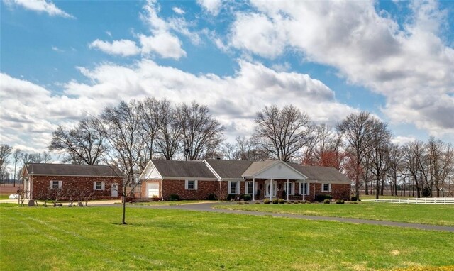 single story home featuring a porch, brick siding, aphalt driveway, a front lawn, and an attached garage