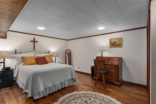 bedroom with wood finished floors, ornamental molding, and baseboards