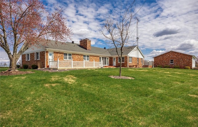 back of property featuring brick siding, a lawn, and a chimney