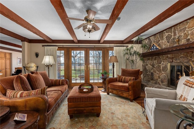 living area with beam ceiling, a ceiling fan, french doors, and a fireplace