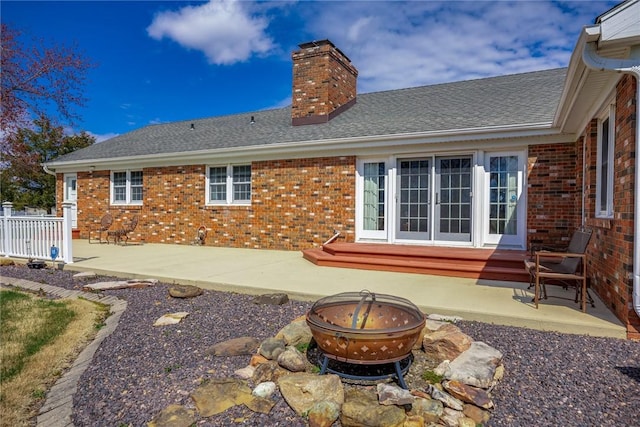 rear view of house with a patio area, a fire pit, brick siding, and a chimney