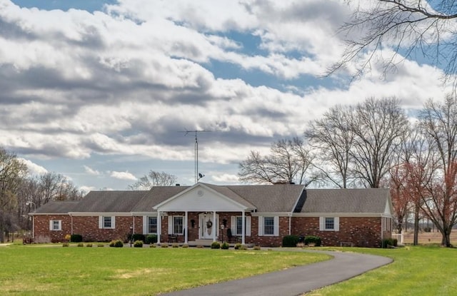 view of front of home with covered porch, brick siding, and a front lawn