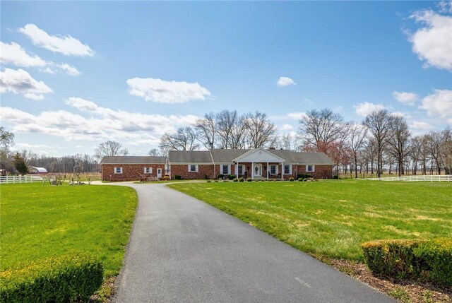 view of front facade with a front yard, fence, and brick siding