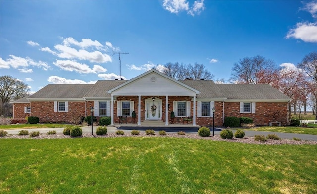 view of front facade featuring covered porch, brick siding, and a front lawn