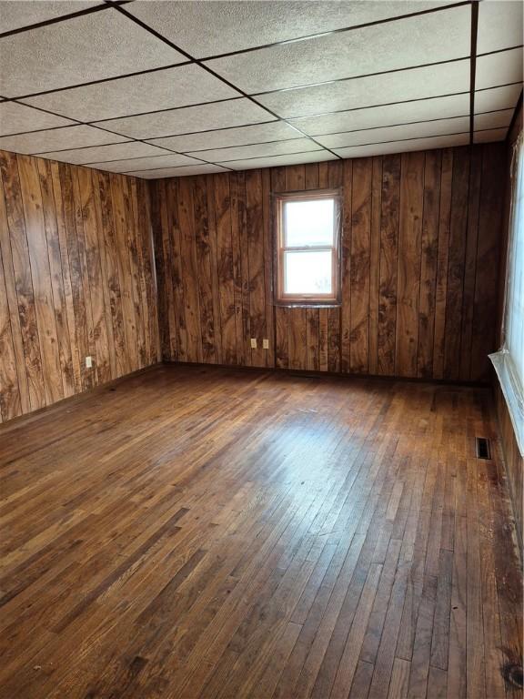 910 Glendale Ave, Tilton, IL 61833 - unfurnished room with a drop ceiling, dark hardwood / wood-style flooring, and wood walls