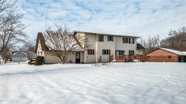 snow covered back of property with a wooden deck