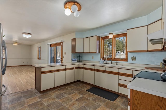 kitchen featuring sink, stainless steel fridge, ceiling fan, cream cabinets, and kitchen peninsula