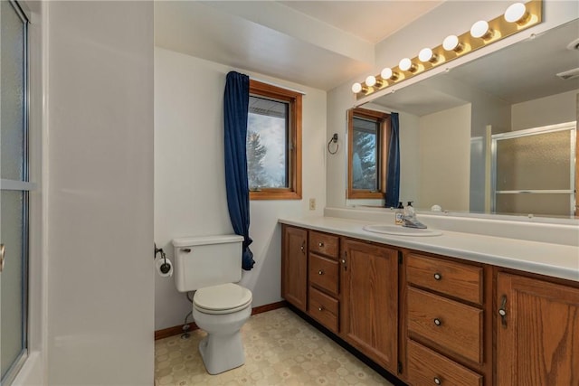 bathroom featuring vanity, a shower with shower door, and toilet