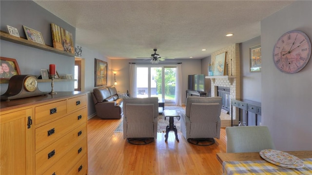 1950 Shore Oak Dr, Decatur, IL 62521 - living room featuring a textured ceiling, light wood-style flooring, a ceiling fan, a brick fireplace, and recessed lighting