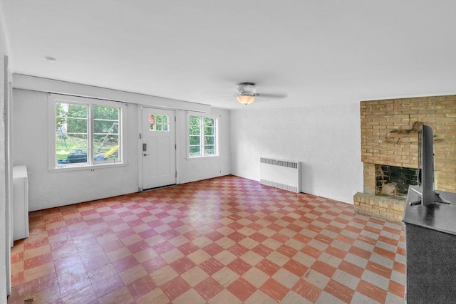 530 Powers Ln, Decatur, IL 62522 - unfurnished living room featuring radiator, light floors, ceiling fan, and a brick fireplace