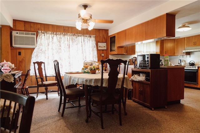 carpeted dining area with ceiling fan, wooden walls, a healthy amount of sunlight, and a wall mounted air conditioner