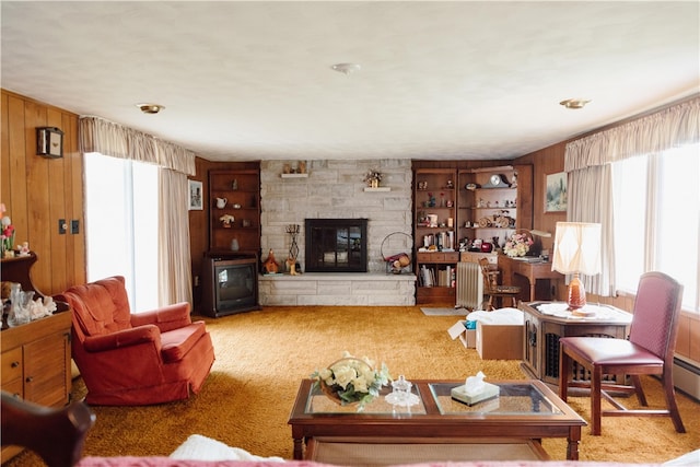 carpeted living room with a stone fireplace and wood walls