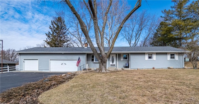 ranch-style home featuring a garage, fence, a front lawn, and aphalt driveway