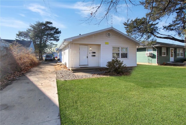 view of front of home with cooling unit, driveway, and a front yard