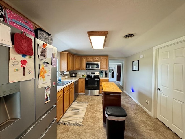 202 Seminary St, Catlin, IL 61817 - kitchen featuring appliances with stainless steel finishes, brown cabinets, light tile patterned flooring, and a kitchen island
