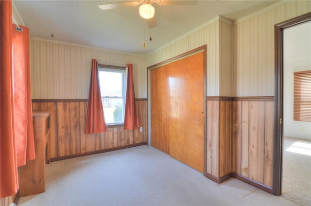 unfurnished bedroom with wallpapered walls, ornamental molding, carpet flooring, and wainscoting