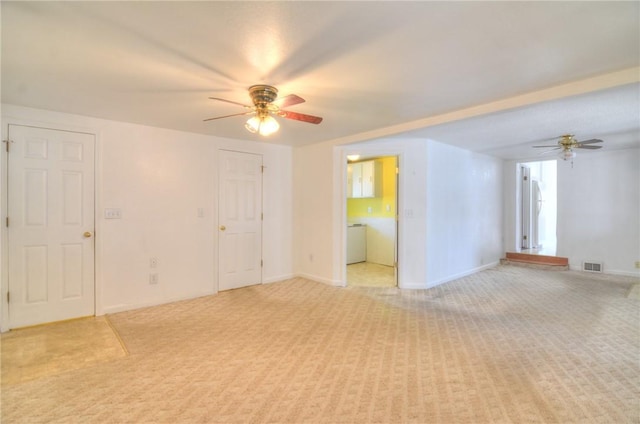 spare room with baseboards, light colored carpet, visible vents, and ceiling fan