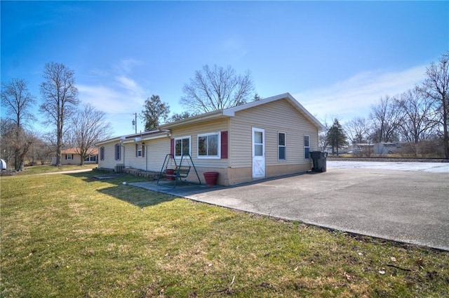 view of front of property featuring aphalt driveway, a patio, and a front yard