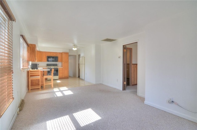 unfurnished living room featuring ceiling fan, baseboards, visible vents, and light carpet