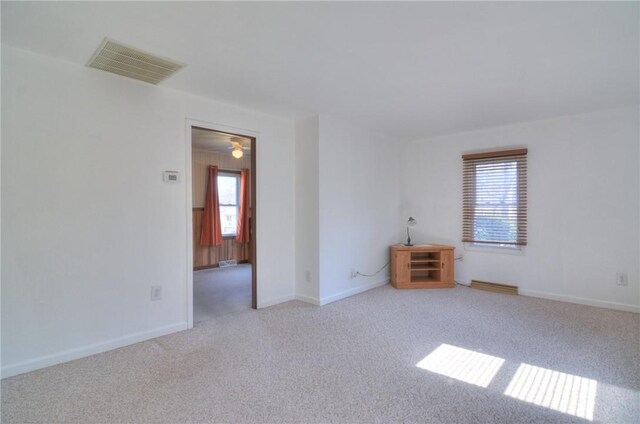 carpeted empty room with plenty of natural light, baseboards, and visible vents